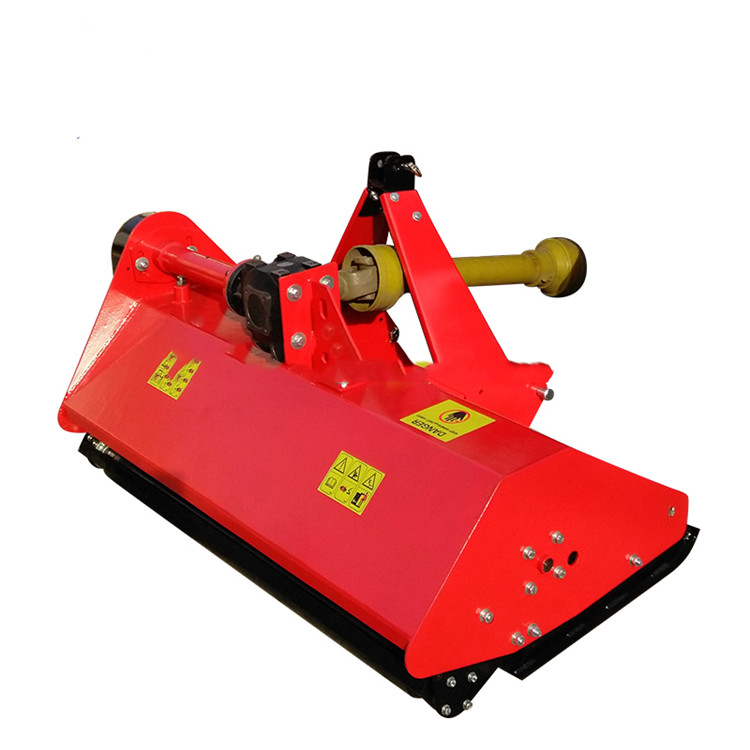 Large flail mower attachment with multiple rotating blades, green and yellow colors, agricultural tractor in background